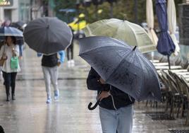 Paraguas bajos para evitar que los vuele el viento, en las calles de Santander.