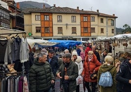 Varias personas hacen sus compras en el mercado, con el paraguas en la mano porque hubo rachas de lluvia durante la jornada.