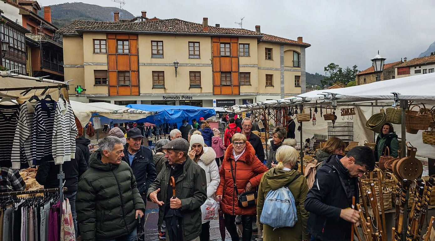 Varias personas hacen sus compras en el mercado, con el paraguas en la mano porque hubo rachas de lluvia durante la jornada.