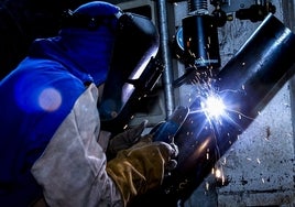 Un soldador trabajando en una pieza industrial.