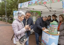 El alcalde de Camargo, Diego Movellán, conversa con una vecina sobre la campaña de recogida de vidrio iniciada en el municipio.