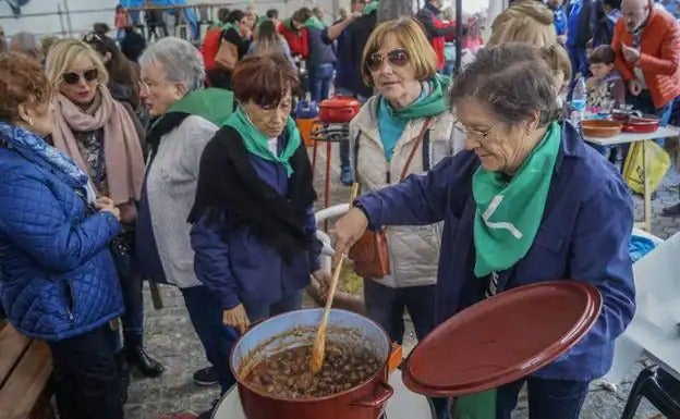 Unas mujeres observan y dan vuelta a los caracoles cocinados por San Martín en Castro Urdiales.