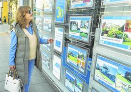 Una mujer consulta las ofertas de una inmobiliaria en el centro de Santander.