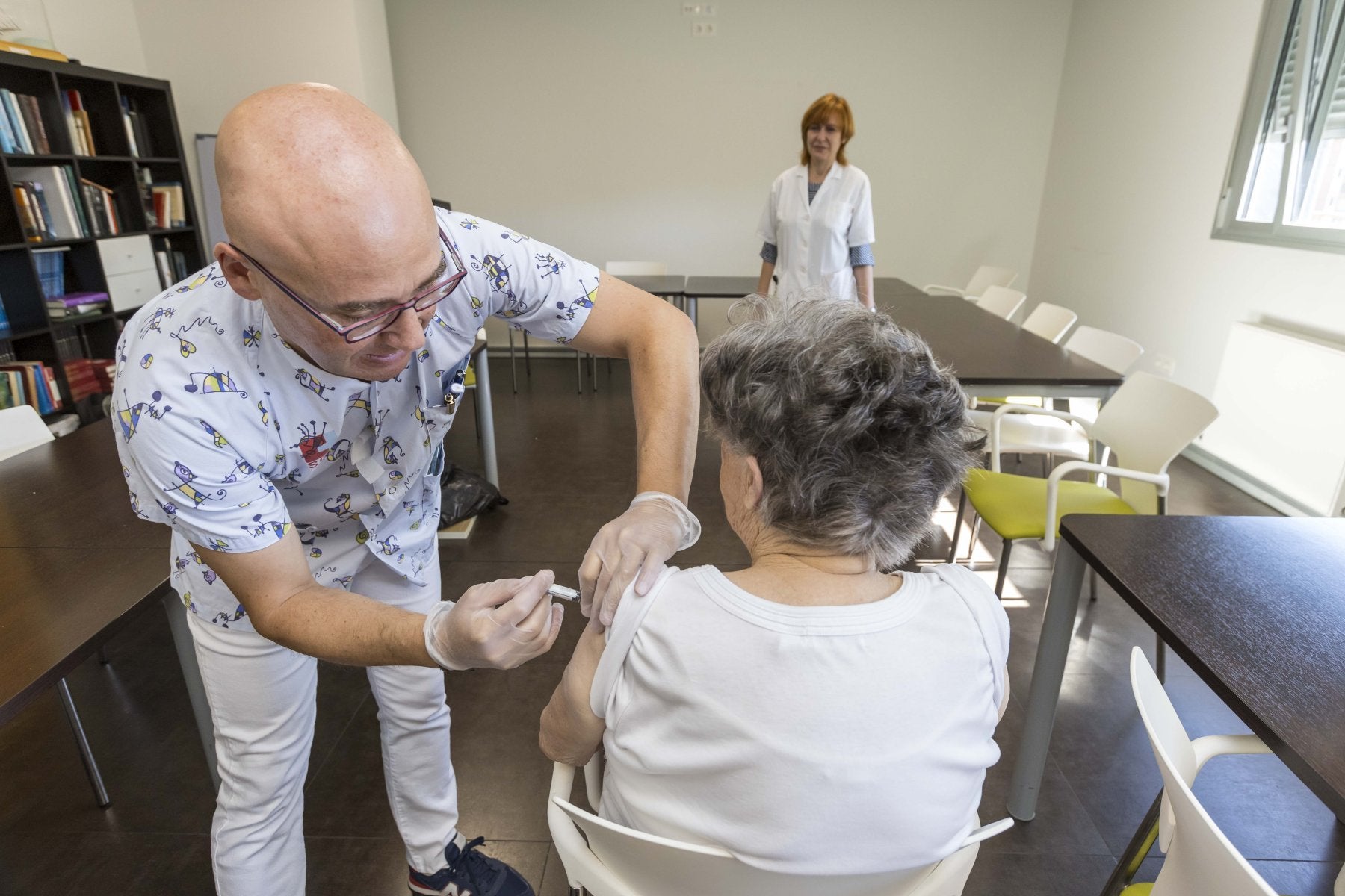 Un enfermero del centro de salud de El Sardinero pone la vacuna de la gripe a una mujer en la residencia Virgen del Faro.