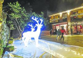 Vecinos de Quijano, en Piélagos, pasean frente a una de las casas decoradas por Navidad con luces y figuras.