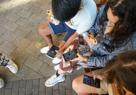Un grupo de menores con el bocadillo y, a la vez, con su teléfono móvil.