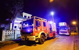 Dos camiones de bomberos aparcados junto a la casa incendiada en la tarde del suceso.