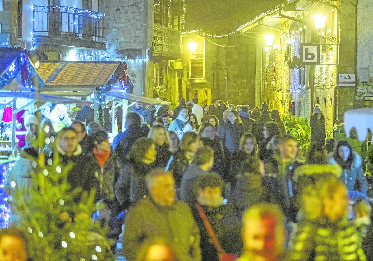 Imagen principal - 1. Al árbol le ha salido un duro competidor, el Camino Real. | 2. El mercado navideño es uno de los alicientes de las fiestas. | 3. Miles de personas pasan cada día por el árbol.