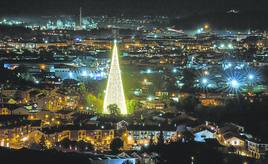 Vista nocturna de Cartes, en primer término y con el árbol de Navidad como punto más destacado. Al fondo, Torrelavega y la zona industrial, donde destaca la chimenea de Solvay.