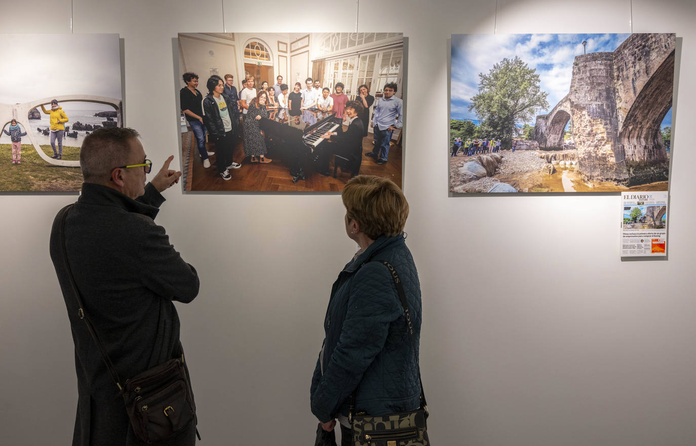 Dos asistentes observan las fotografías expuestas en la Casa de Cultura de Colindres.