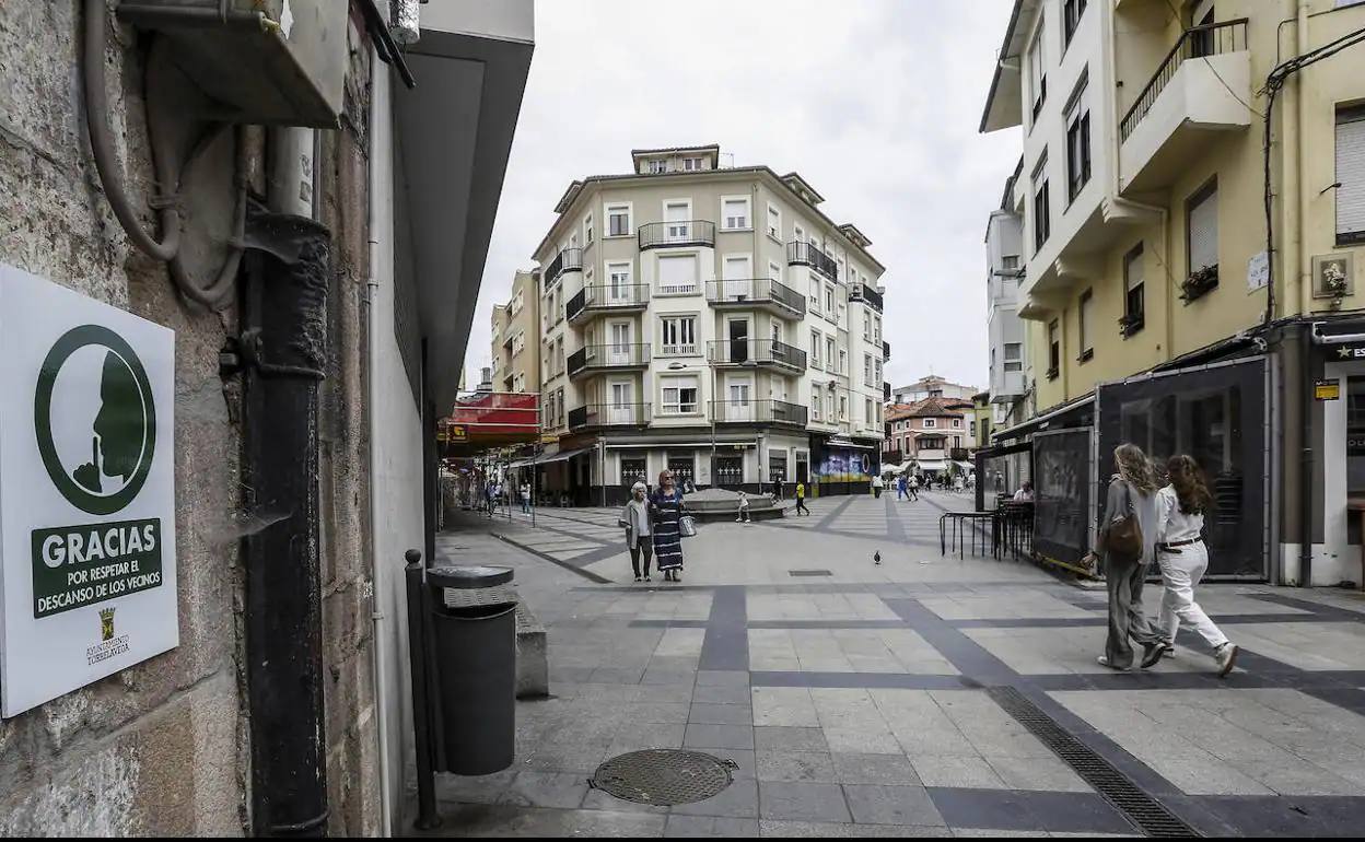 Varias vecinas caminan por el barrio San José, la zona de vinos, ante un cartel municipal colocado para rogar silencio a los visitantes.