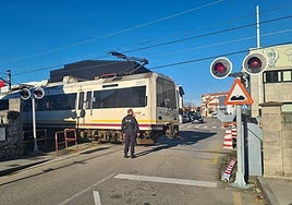 Un policía se encarga de la seguridad en el paso a nivel del Paseo del Niño, este martes, en Torrelavega, con la barrera tirada en el suelo (a la derecha).