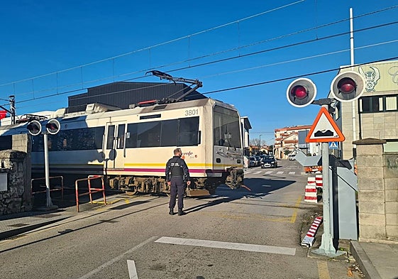 Un policía se encarga de la seguridad en el paso a nivel del Paseo del Niño, este martes, en Torrelavega, con la barrera tirada en el suelo (a la derecha).