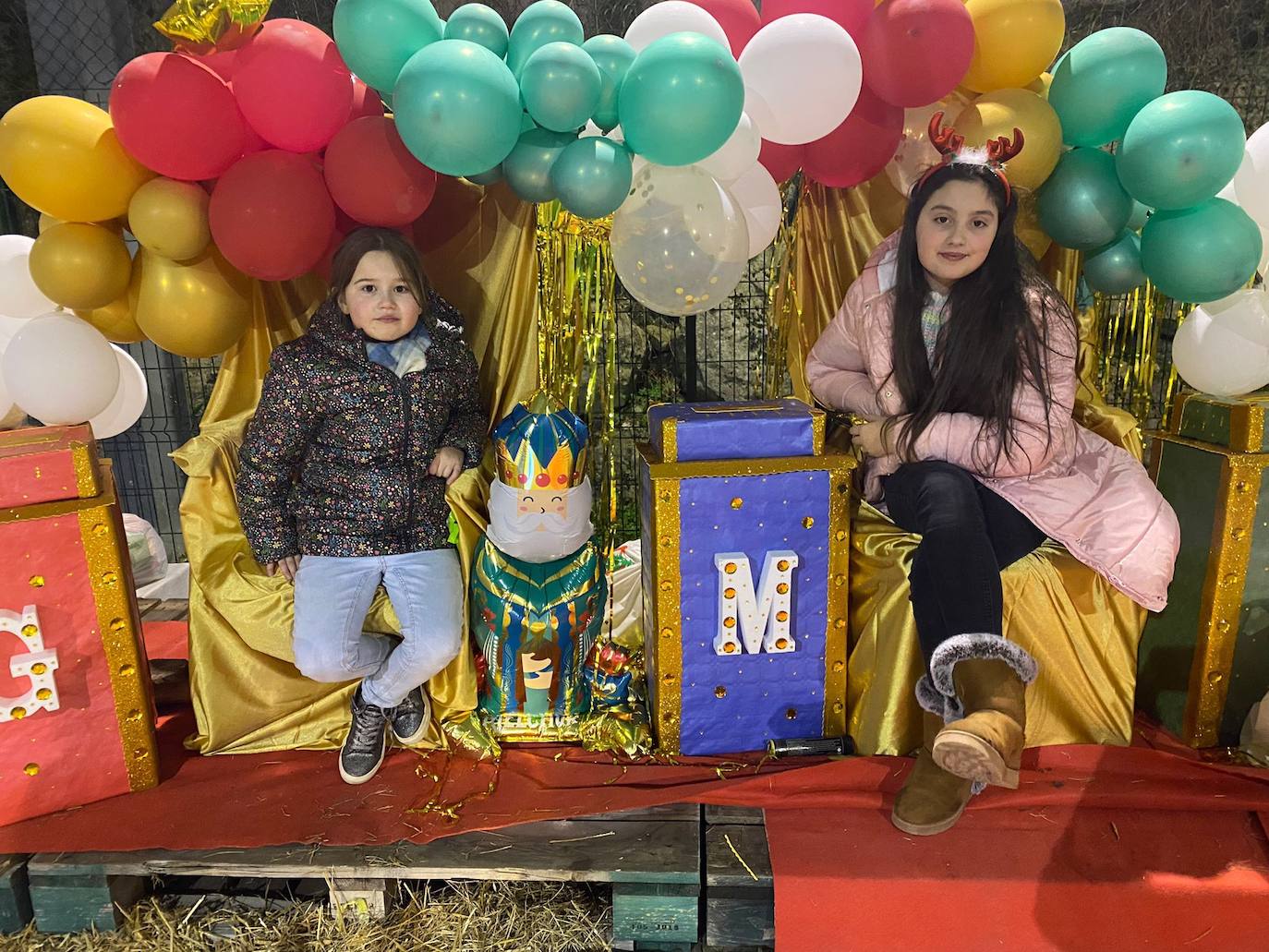 Dos niñas de la zona sentadas en los tronos de los carteros reales. 