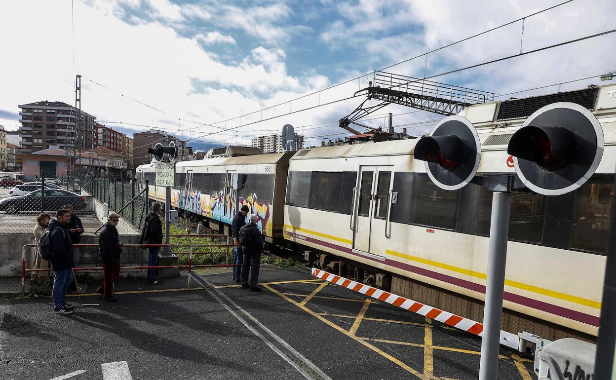 Vecinos esperan en el paso a nivel de Pablo Garnica, el viernes, durante la llegada de un tren de Feve a la capital del Besaya.