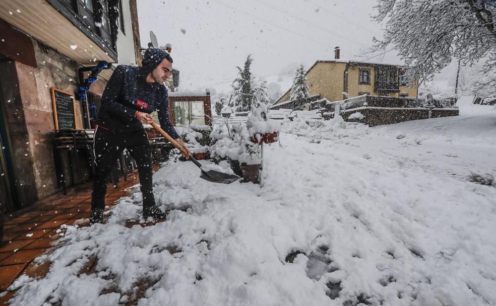 Un joven palea la nieve a la entrada del Mesón Ventorrillo, en el municipio de Pesquera. 