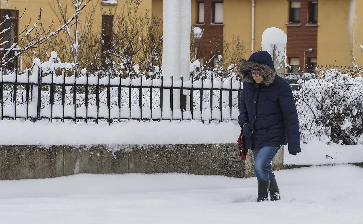 Una mujer camina, este jueves, por Reinosa totalmente cubierto de blanco,