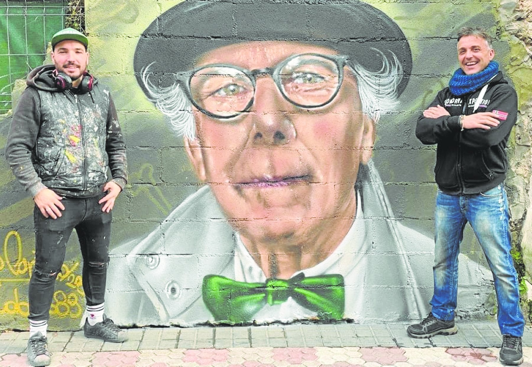 Steve Camino, a la izquierda, posa ante el grafiti pintado en la calle del Paseo, a la altura del bar Sildavia, cuyo muro ha cedido Santos Gómez. 