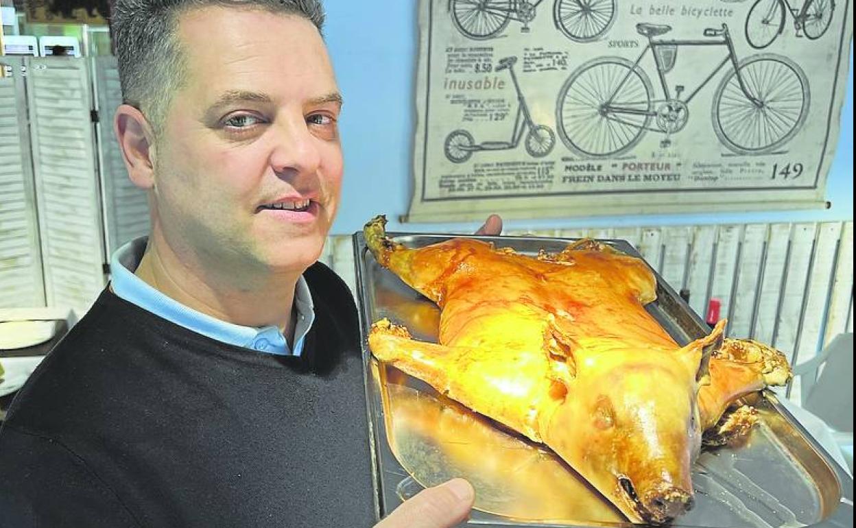 Javier Allende, propietario del negocio, muestra el cochinillo al horno. 