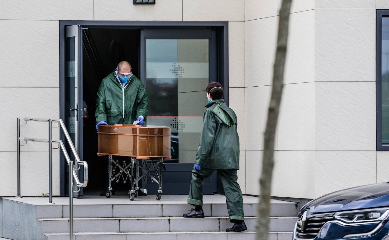 Operarios de una funeraria trasladan el cadáver de un fallecido en una residencia durante la pandemia.