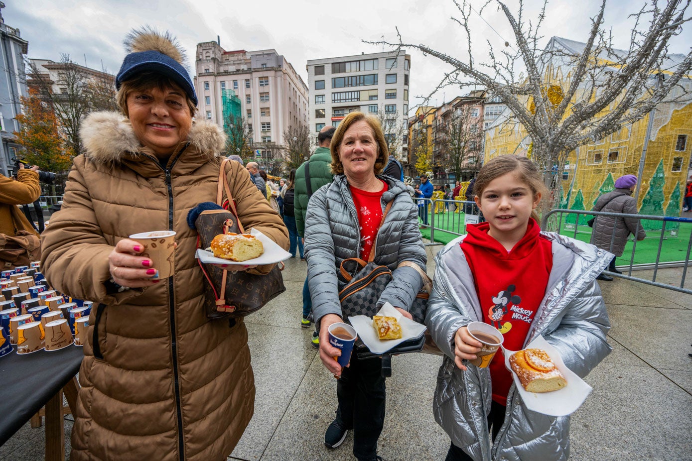 Tres de las asistentes muestran su desayuno solidario. 