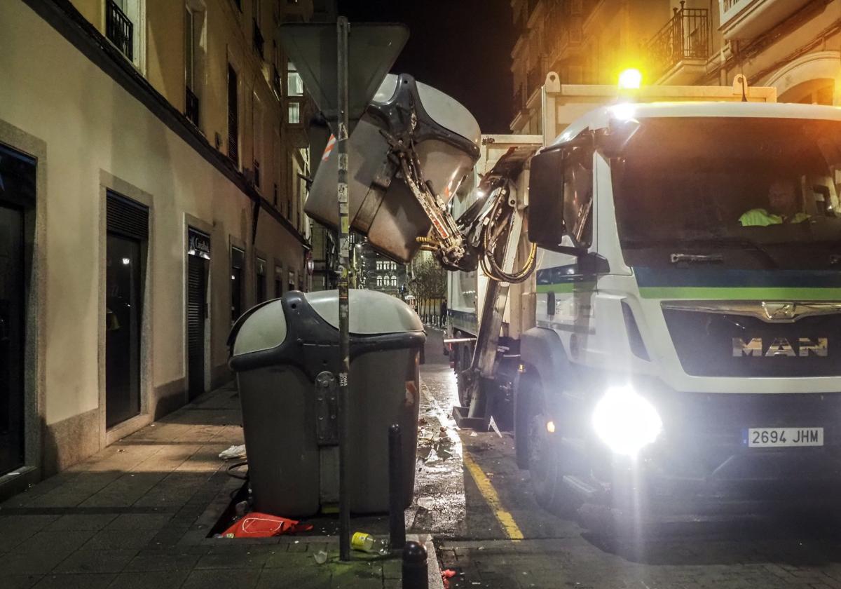 Empleados del servicio de Limpieza Viaria trabajan recogiendo contenedores de basura en el centro de Santander.