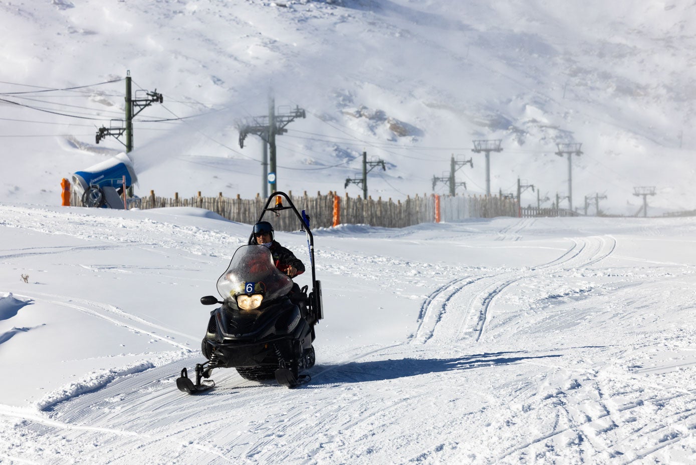 Un operario circula por las pistas con una moto de nieve.