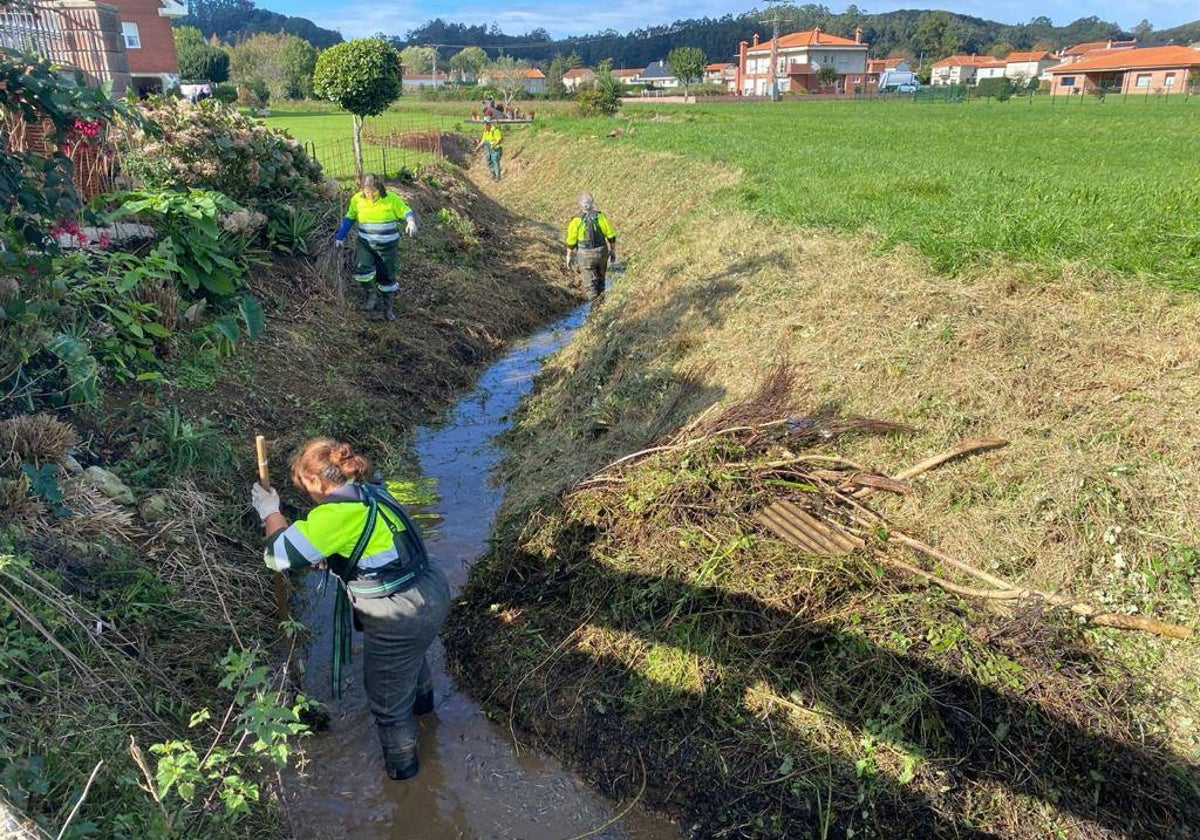 Un grupo de operarios realizando el mantenimiento y limpieza de un arroyo en Camargo.