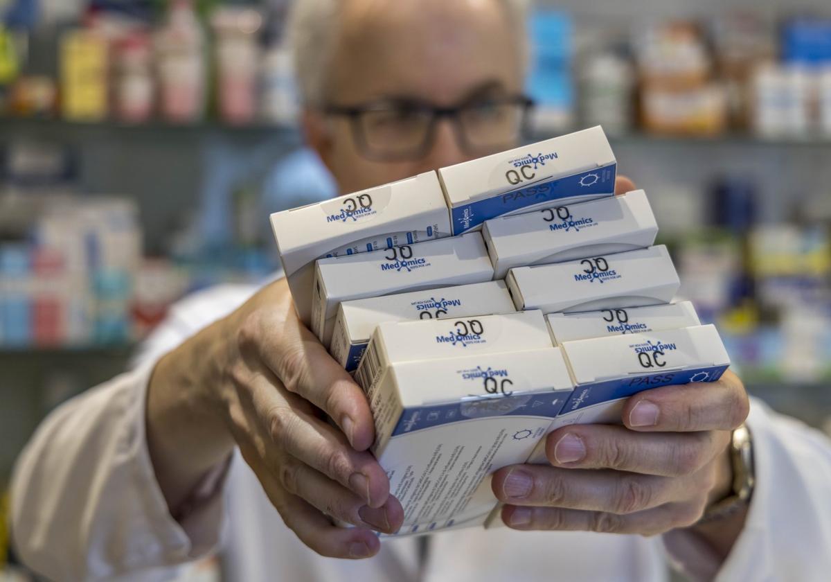 Un farmacéutico muestra cajas del test del covid.