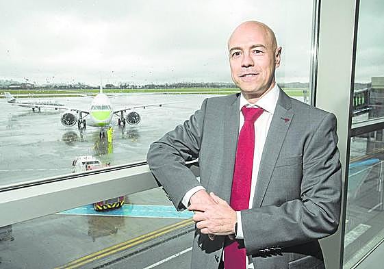 Miguel Ángel Salgado posa en una sala del aeropuerto con un avión sobre la pista como fondo.