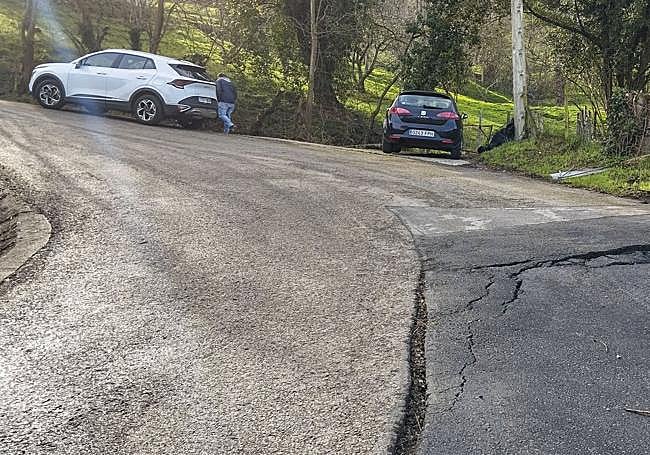 José Manuel Martínez muestra la grieta de la carretera de acceso al barrio de La Contrina.