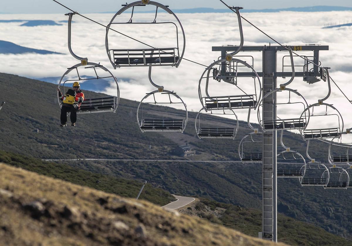 Un trabajador de la estación se desplaza en un remonte sin que al fondo se atisbe el más mínimo rastro de la nieve.