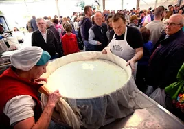 Los queseros sostienen el queso más grande entre el público