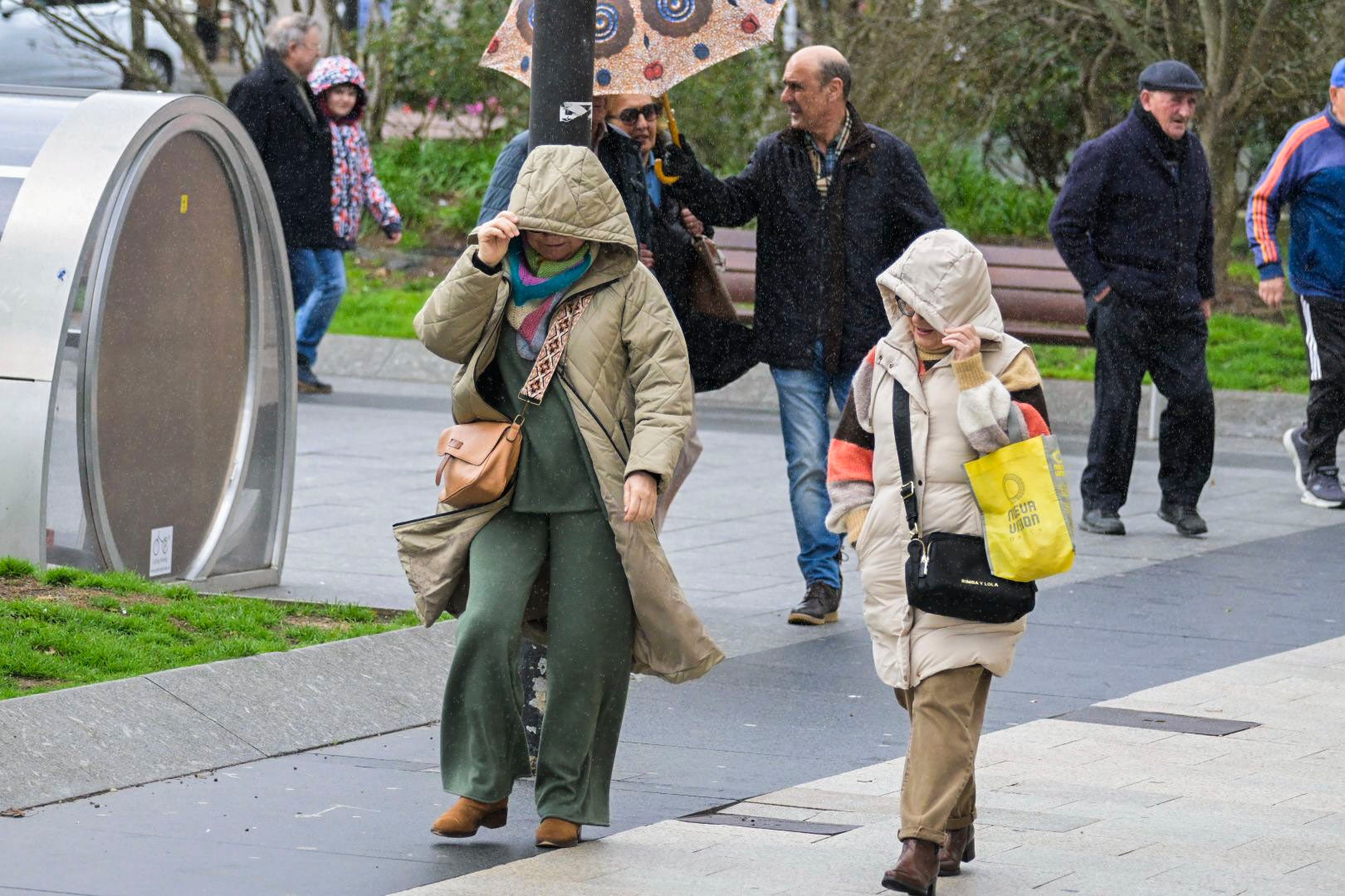 Dos mujeres se protegen del viento y la lluvia en Santander, este lunes.