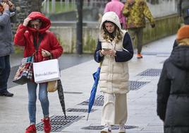 Paraguas, abrigos y capuchas para protegerse del temporal este lunes en Santander