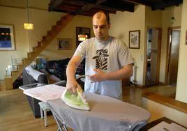 Un hombre plancha una camiseta en su casa.