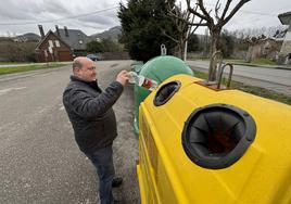 Un hombre deposita una botella de plástico en el contenedor amarillo de reciclaje.