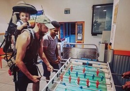 'Ric' Fernández, con su hija a la espalda, jugando al futbolín junto a Lebron, un refugiado en Ventimiglia (Italia)