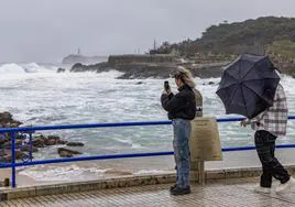 Una pareja haciendo fotos al oleaje ayer, frente a la Magdalena, con Mouro al fondo.