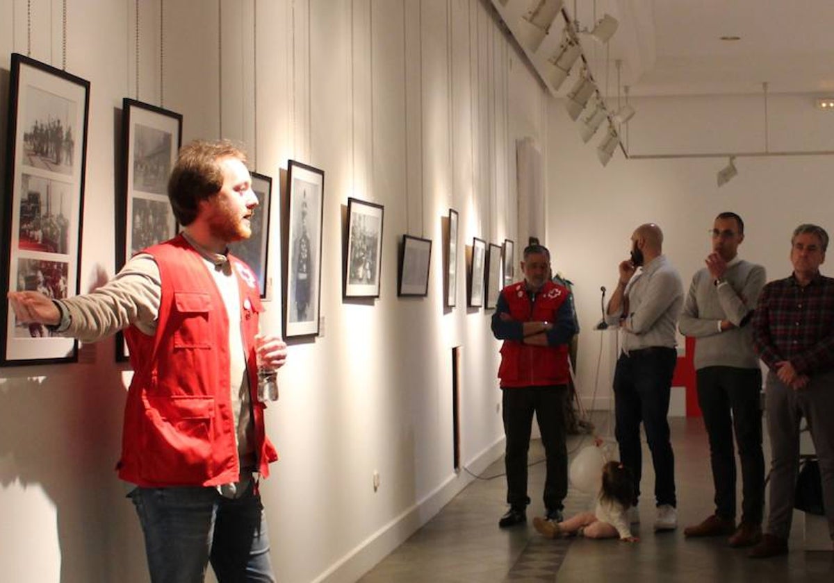 Un miembro de la Cruz Roja explica parte de la exposición de imágenes a miembros del equipo de gobierno.