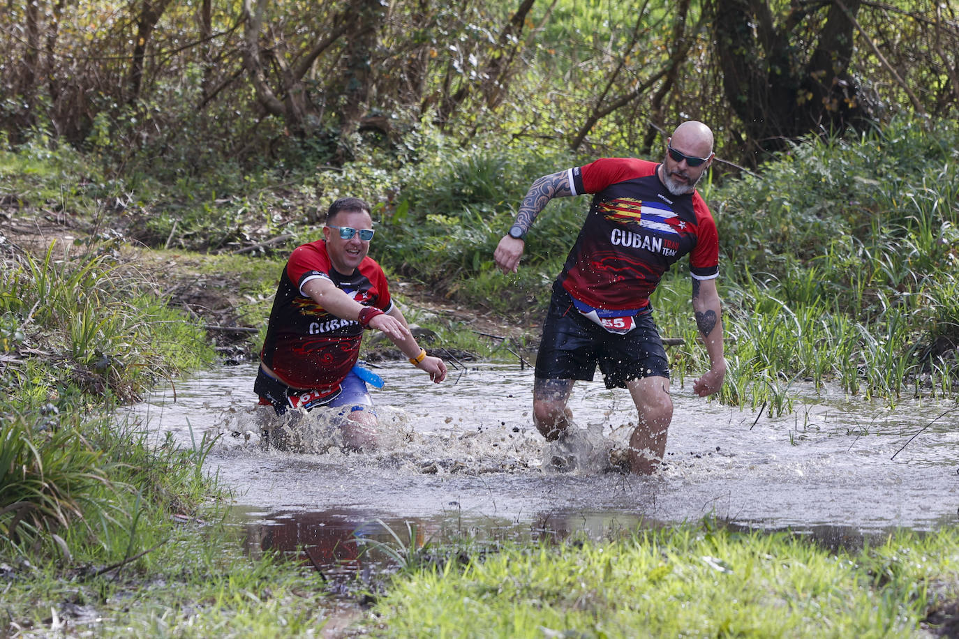 Dos atletas cruzan un tramo de agua en el trail.