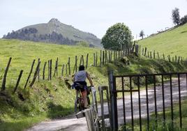 Un ciclista circula por la sierra del Dobra con el pico de La Capía al fondo.