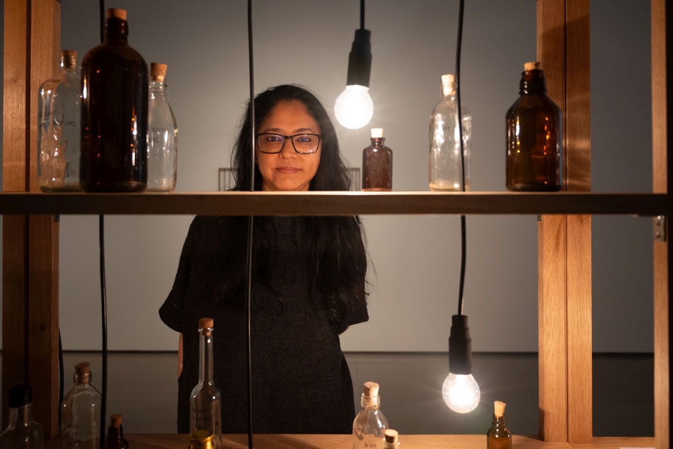 Shilpa Gupta, la artista de Bombay, posa tras las botellas de vidrio de boticario cuyas etiquetas contienen versos de poetas censurados