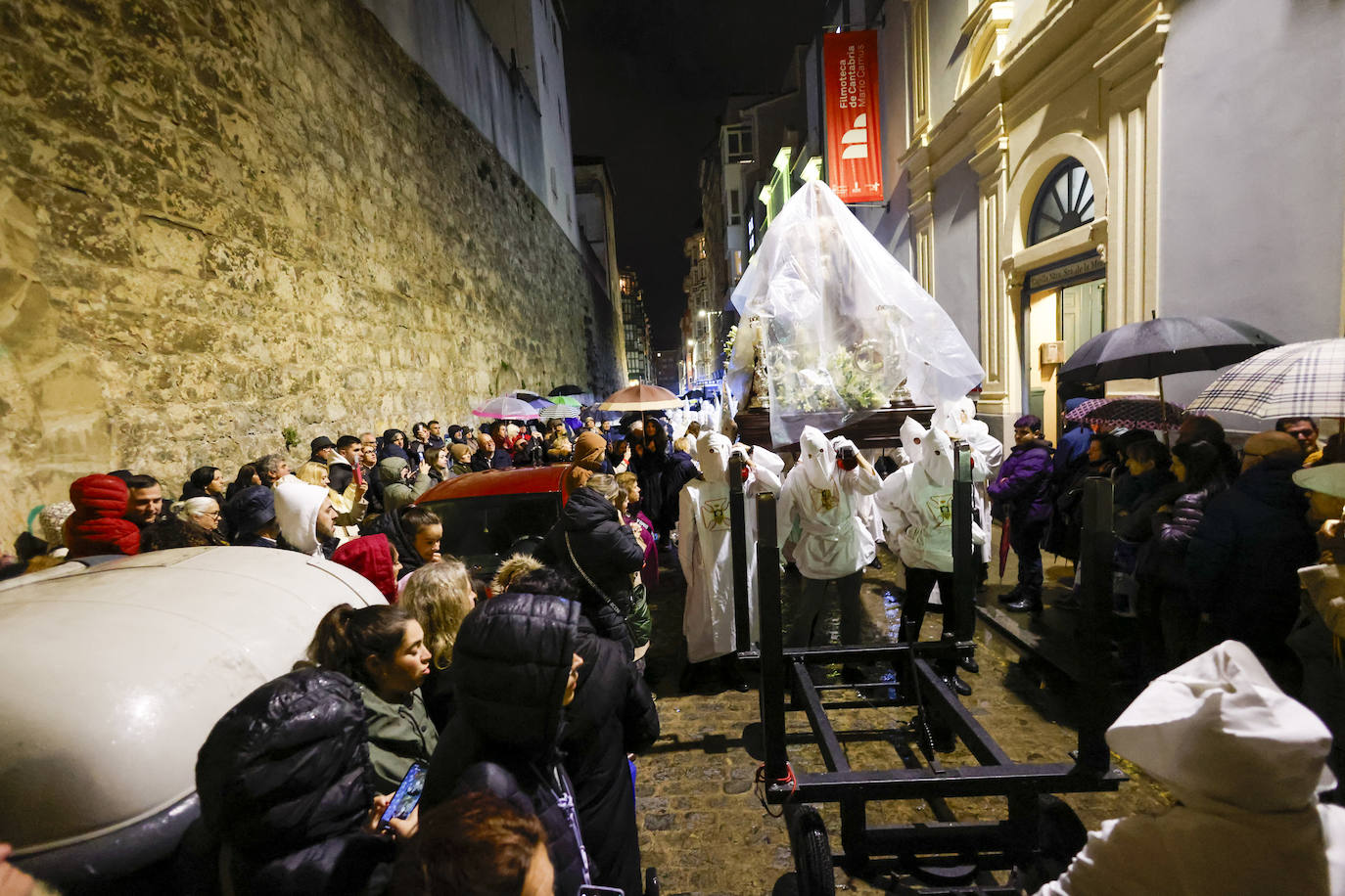 La Merced, protegida con plásticos, durante el traslado hasta la carpa de La Porticada, acompañada de los cofrades