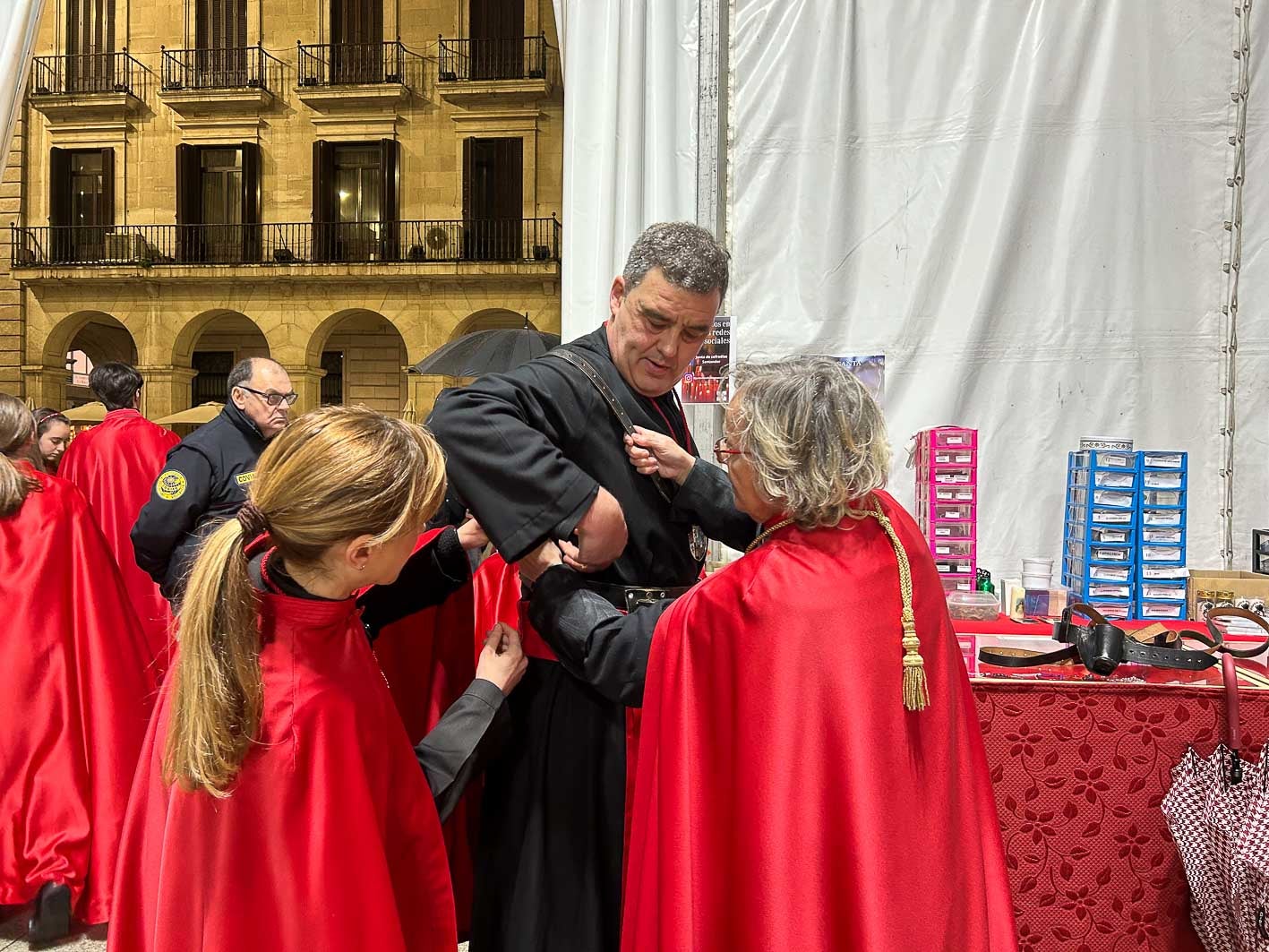 La Hermana Mayor, Mar Alcántara, y una de las cofrades ayudan a uno de los cargueros a ponerse el arnés.