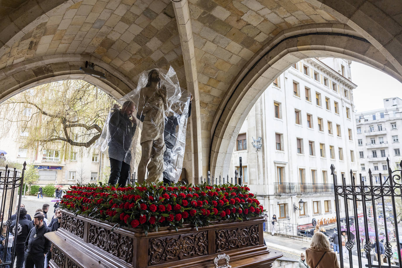 La imagen de 'Cristo Resucitado' antes de salir es portegida por un plástico ante el riesgo de lluvia