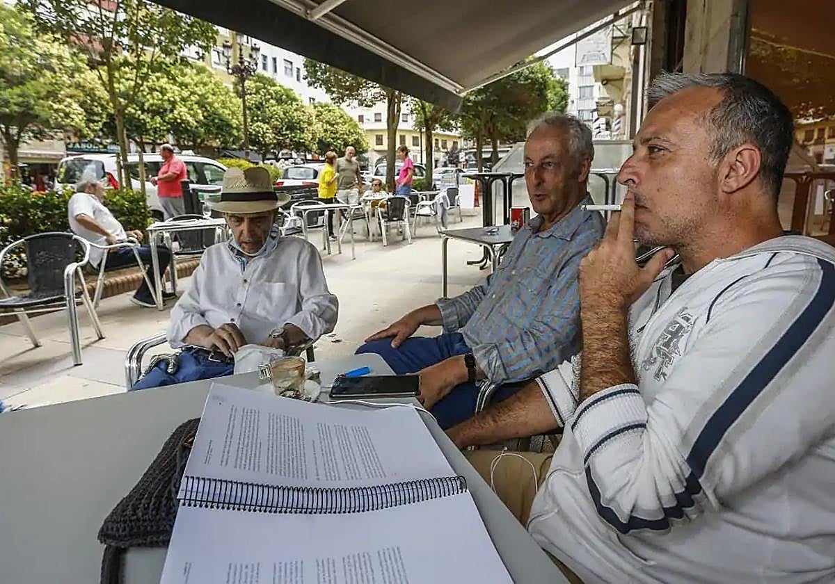 Tres hombres conversan en la terraza de un establecimiento de Torrelavega.