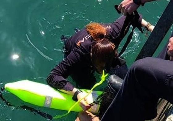 Una agente de policía se introduce en el agua al rescate de la chica.