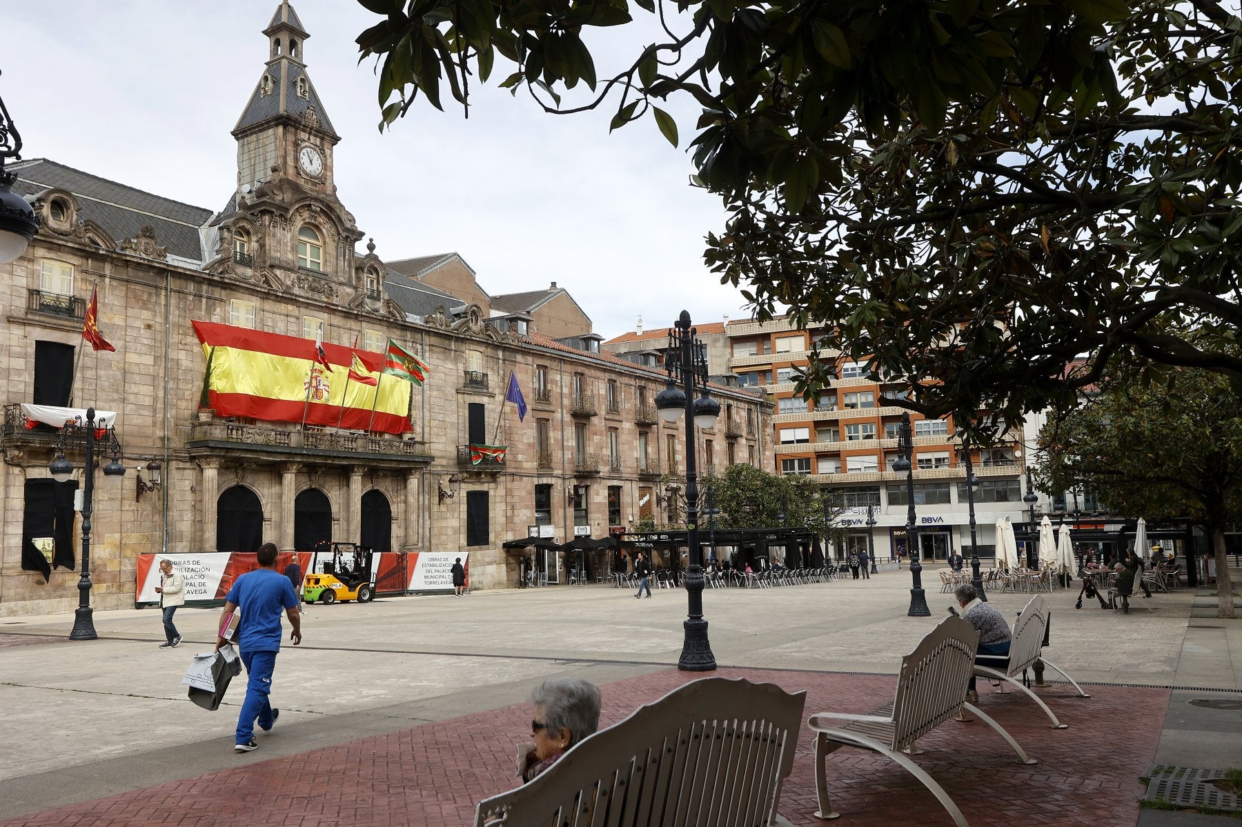 Vecinos caminan frente al Palacio municipal de Torrelavega, consolidado estructuralmente y cerrado al público desde hace años.