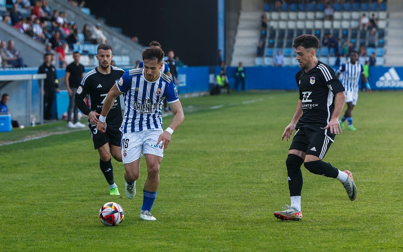 Chus Ruiz controla la pelota ante dos jugadores del Langreo.